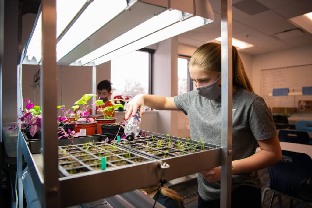 Girl watering plants at Williston Innovation Academy