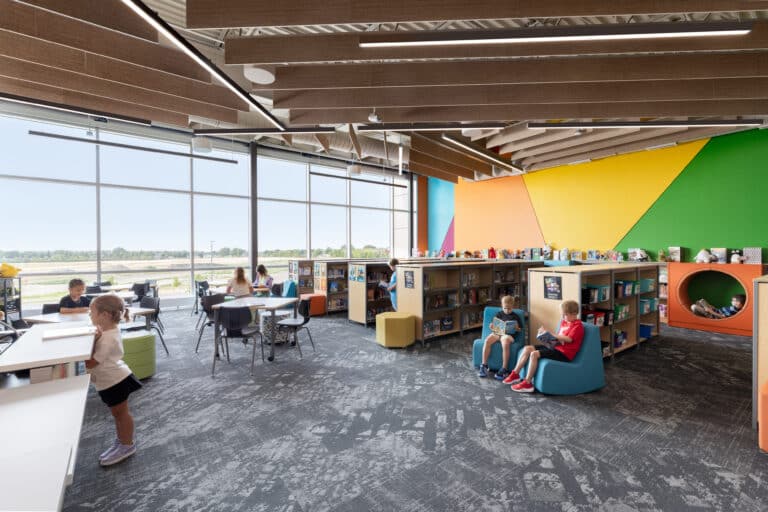 Sloulin media center with children enjoying the library and an adult helping check out books.
