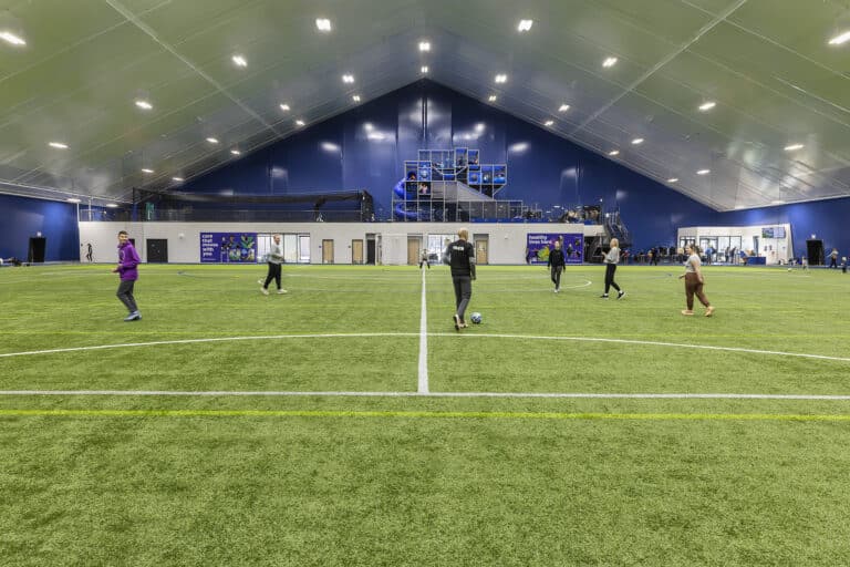 Athletes practice soccer at an indoor municipal fieldhouse